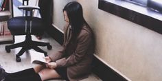 a woman sitting on the floor reading a book