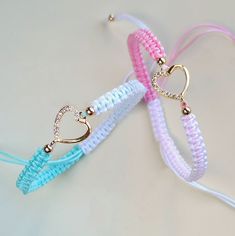 three bracelets with heart charms on them sitting next to each other in different colors