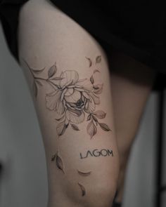 a woman's thigh with flowers and the word moon tattooed on it