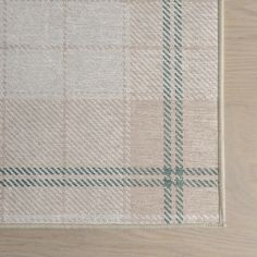 a beige and green checkered rug on top of a wooden floor