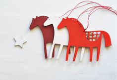 two red and white horses are hanging from strings on the wall next to each other