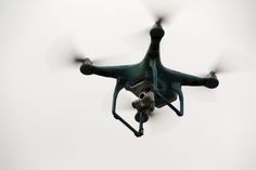 a black and white photo of a small quadcopter flying in the sky