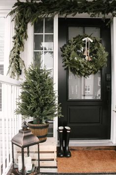 the front door is decorated for christmas with evergreen wreaths