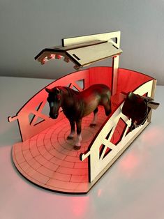 a paper model of two horses standing on a red and white platform with lights in the background