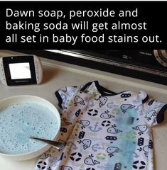 a baby's bodysuit sitting on top of a counter next to a bowl of food