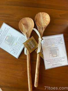 two wooden spoons with tags attached to them sitting on a table next to an open book