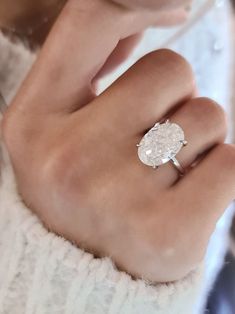 a woman's hand wearing a ring with a diamond on the center and side