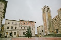 an old building with a christmas tree in the middle and two tall buildings behind it