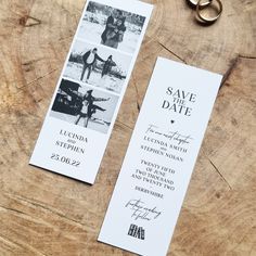 wedding save the date cards on top of a wooden table next to two gold rings