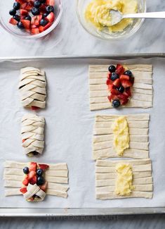 some fruit and pastry items on a baking sheet with bowls of yogurt, strawberries, and blueberries