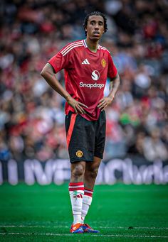 a man standing on top of a soccer field wearing a red shirt and black shorts