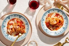 two plates of pasta and wine on a table