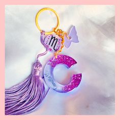 a pink and purple keychain with a tassel hanging from it's side