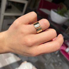 a person's hand with a gold and silver ring on top of their finger