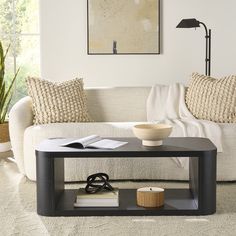 a living room with a white couch and coffee table in front of a painting on the wall