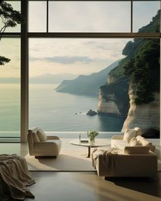 a living room filled with furniture next to a large window overlooking the ocean and cliffs