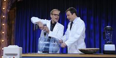 two men in white lab coats standing next to a blender on a tv set