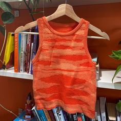 an orange tank top hanging on a book shelf