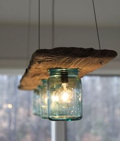 a mason jar hanging from a light fixture in front of a window with trees outside