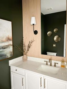 a bathroom with two sinks and a large painting on the wall behind it's mirror