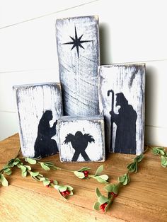 three wooden blocks decorated with silhouettes of people and a star on top of them