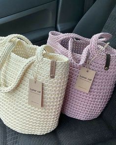 three knitted bags sitting in the back seat of a car with tags on them