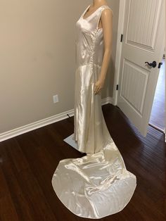 a mannequin dressed in a white dress on a wooden floor next to a door