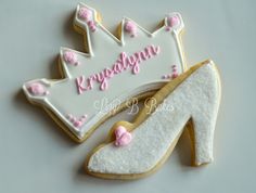 a decorated cookie with a shoe and tiara next to it on a white surface