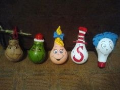 five small toy bowling pins lined up in a row with faces painted on them,