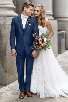 a bride and groom standing together in front of columns