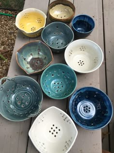 many bowls are lined up on a wooden table with holes in the bottom and sides