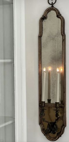 a mirror hanging on the wall with candles in it