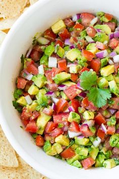 a white bowl filled with guacamole and salsa surrounded by tortilla chips