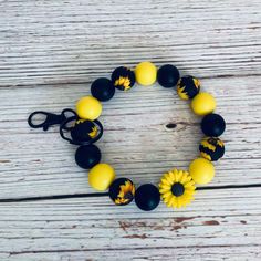 a yellow and black bracelet with sunflowers on it sitting on a wooden table