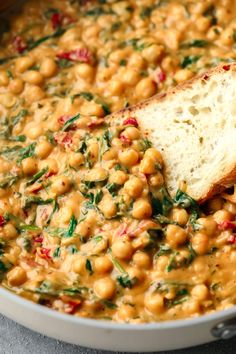 a bowl filled with chickpeas and spinach next to a piece of bread