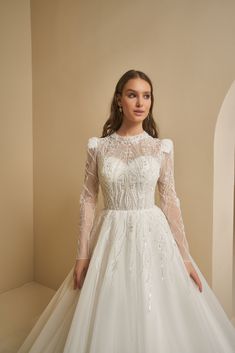 a woman wearing a wedding dress with sheer sleeves and beaded details on the shoulders