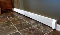 a radiator on the floor in a room with tile floors and gray walls