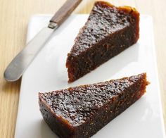 two pieces of chocolate cake on a white plate with a knife and fork next to it