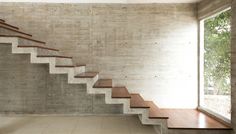 an empty room with concrete walls and wooden steps leading up to the second floor window