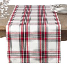 a plaid table runner on top of a wooden table with wine glasses and silverware