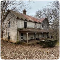 an old run down house in the middle of some trees and leaves on the ground