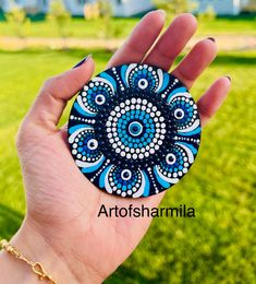 a hand holding a blue and white circular object in it's left hand, with grass in the background