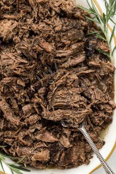 shredded beef in a white bowl with rosemary sprigs on the side, ready to be cooked