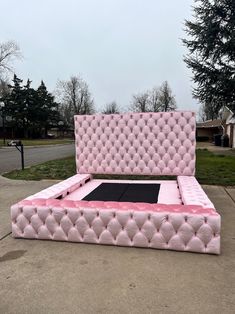 a pink bed sitting on top of a sidewalk