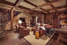 a living room filled with furniture and a fire place next to a stair case in front of a stone fireplace