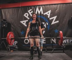 a woman standing in front of a barbell