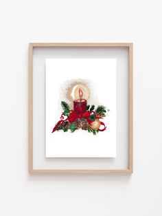 a red candle surrounded by holly and christmas decorations in a wooden frame on a white wall