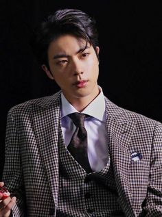 a young man in a suit and tie holding a piece of fruit while sitting down