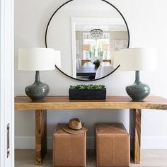 a living room with a mirror and two lamps on top of a table next to a couch