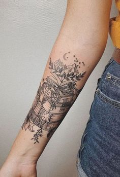 a woman's arm with a tattoo on it that has books and flowers on it